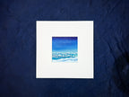 Framed artwork of a blue sky with clouds on a dark blue textured background