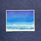 Small painting of a snowy landscape with mountains on a textured blue background