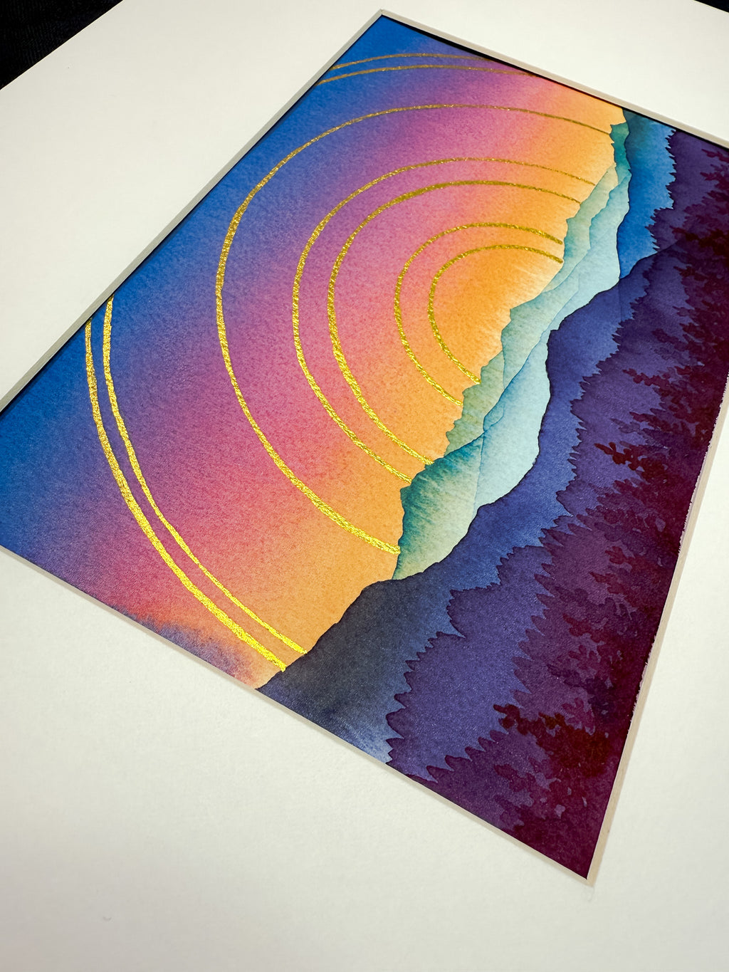 Colorful abstract artwork with golden circles framed in a white mat. 