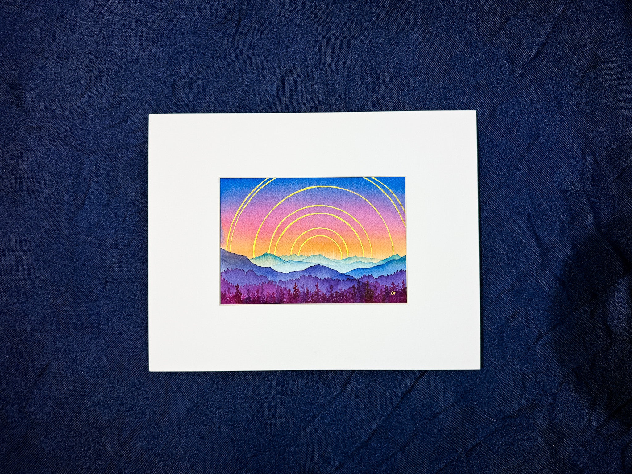 Art print of a colorful mountain landscape with concentric circles on a dark blue fabric background.