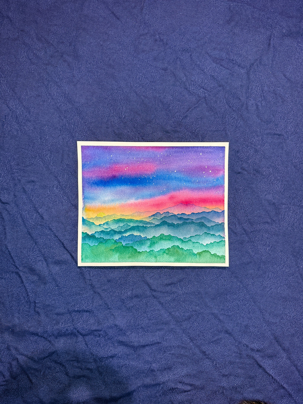 Colorful mountain landscape painting on a textured blue surface