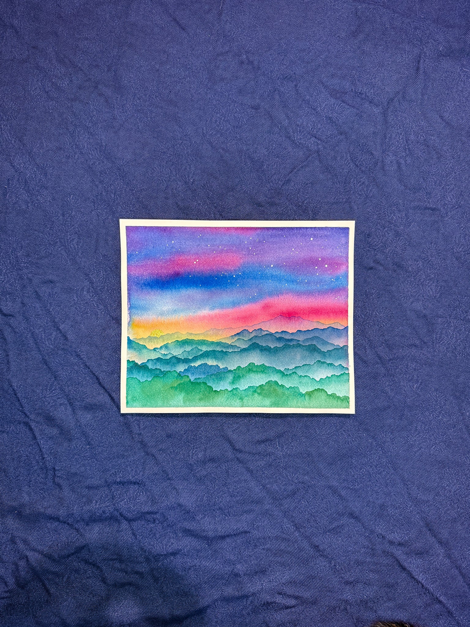 Colorful mountain landscape painting on a textured blue surface