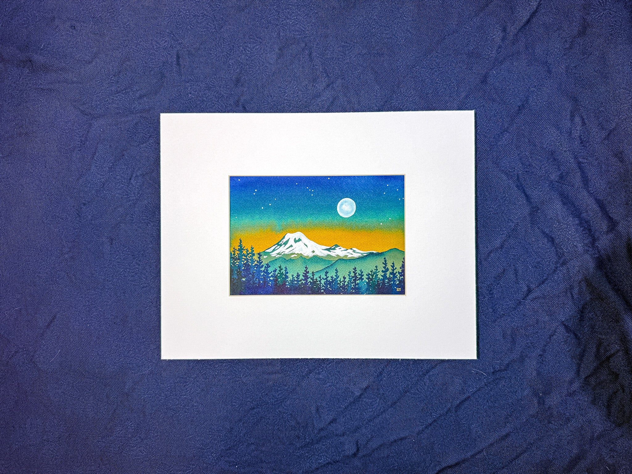 Small painting of a mountain landscape with trees and a moon on a blue textured background